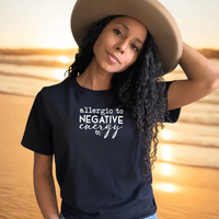 Woman wearing a black t-shirt with 'allergic to negative energy' text and a beige hat.