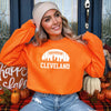 Football with Downtown Cleveland Skyline cutout and CLEVELAND underneath - both in White HTV on an Orange Gildan 18000 Crewneck sweatshirt.