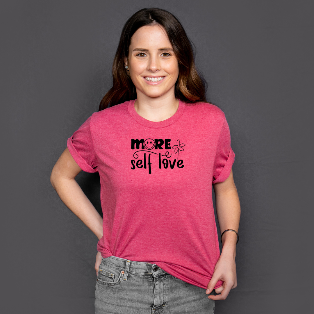 Woman wearing a pink t-shirt with 'More Self Love' text on a dark background