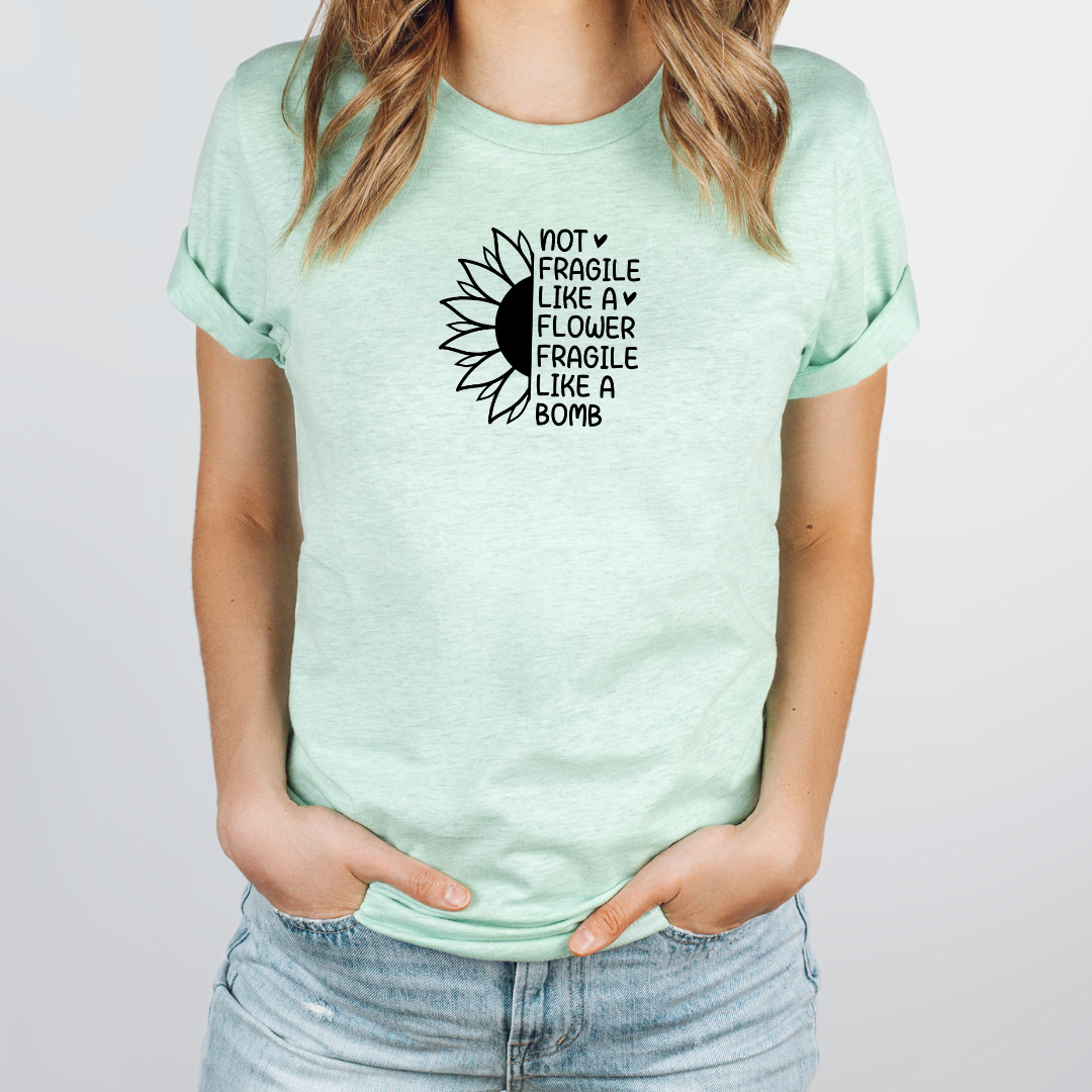 Person wearing a mint green t-shirt with a sunflower graphic and text.
