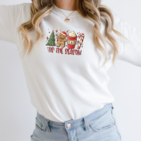 Woman wearing a White Gildan 81000 Crewneck Sweatshirt with a DTF image in red with text tis the season. The image includes Christmas Tree, gingerbread man, hot beverage, and a candy cane