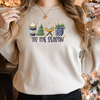 Woman wearing a Sand Gildan 81000 Crewneck Sweatshirt with a DTF image in deep blues, green, and gold with text tis the season. Image includes hot beverage, Christmas Tree, gift with bow, baby Jesus in a manger. 