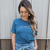A woman wearing a Heather Deep Teal Bella Canvas t-shirt with white text reading Yes, I'm an only child No I'm not lonely. Part of Moxie Momma's exclusive only child line.