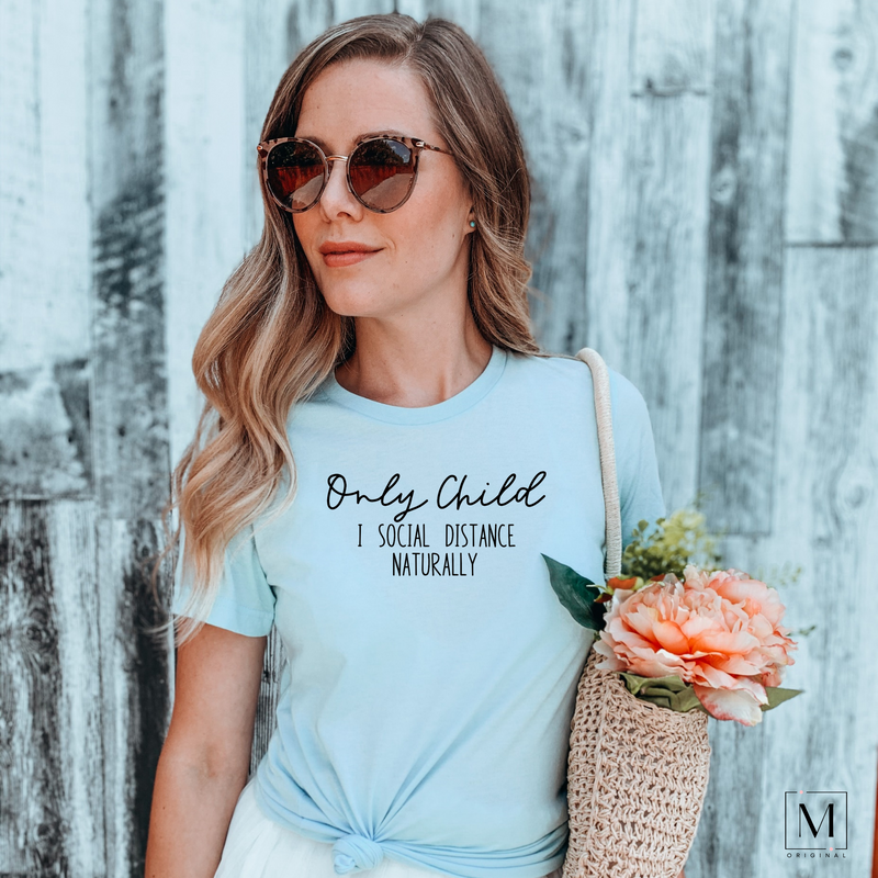 A woman in a Bella Canvas 3001cvc heather ice blue t-shirt with black lettering reading Only child I social distance naturally. Part of Moxie Momma's exclusive only child line.