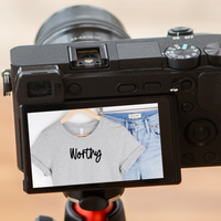 A camera with screen displaying the t-shirt as a reflection with the text reading Worthy.