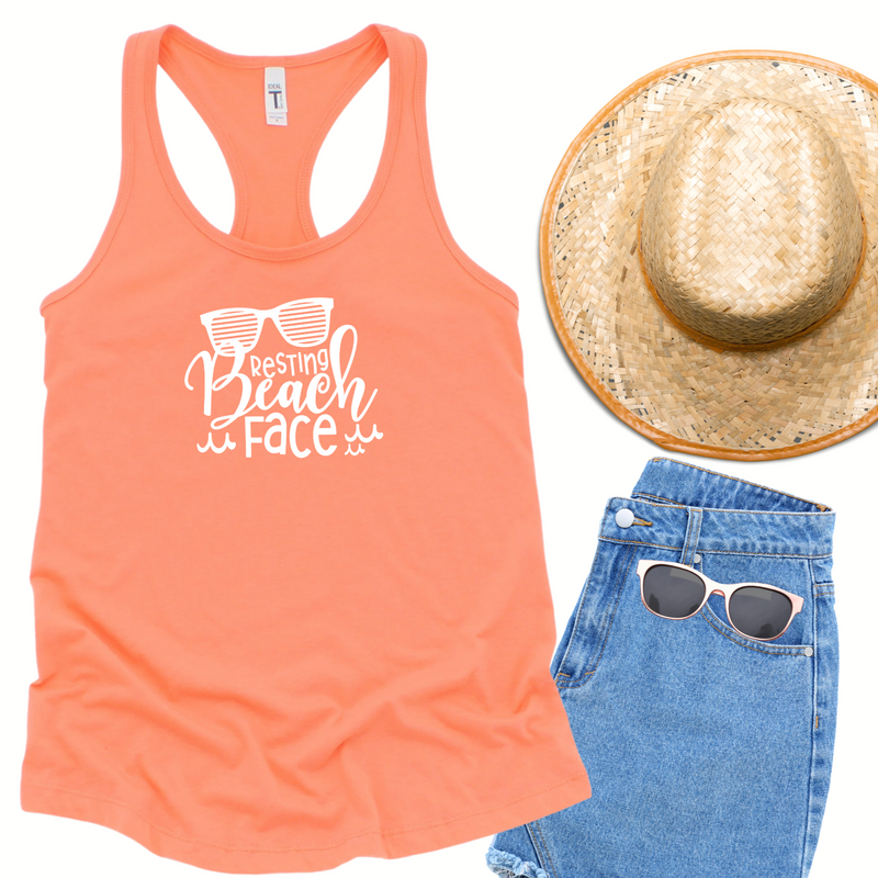 Sunglasses with resting beach face in white on a bright orange 1533 Next Level racerback tank top.